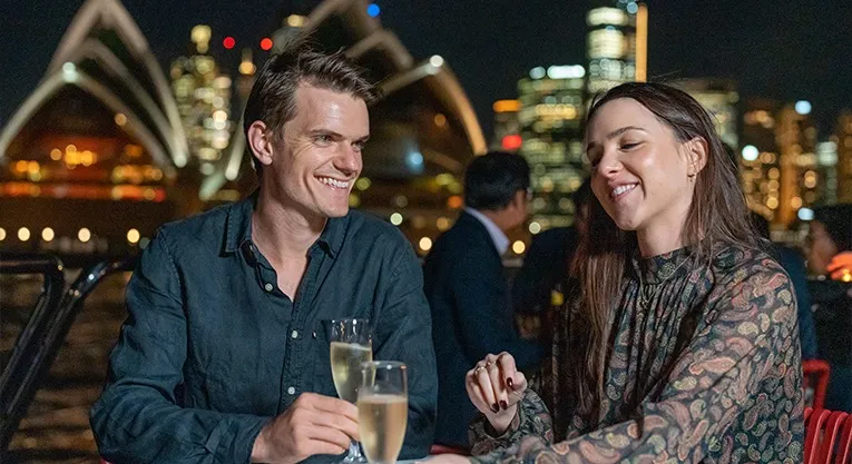 Couple enjoying a romantic dinner cruise on Sydney Harbour with the Opera House visible in the background