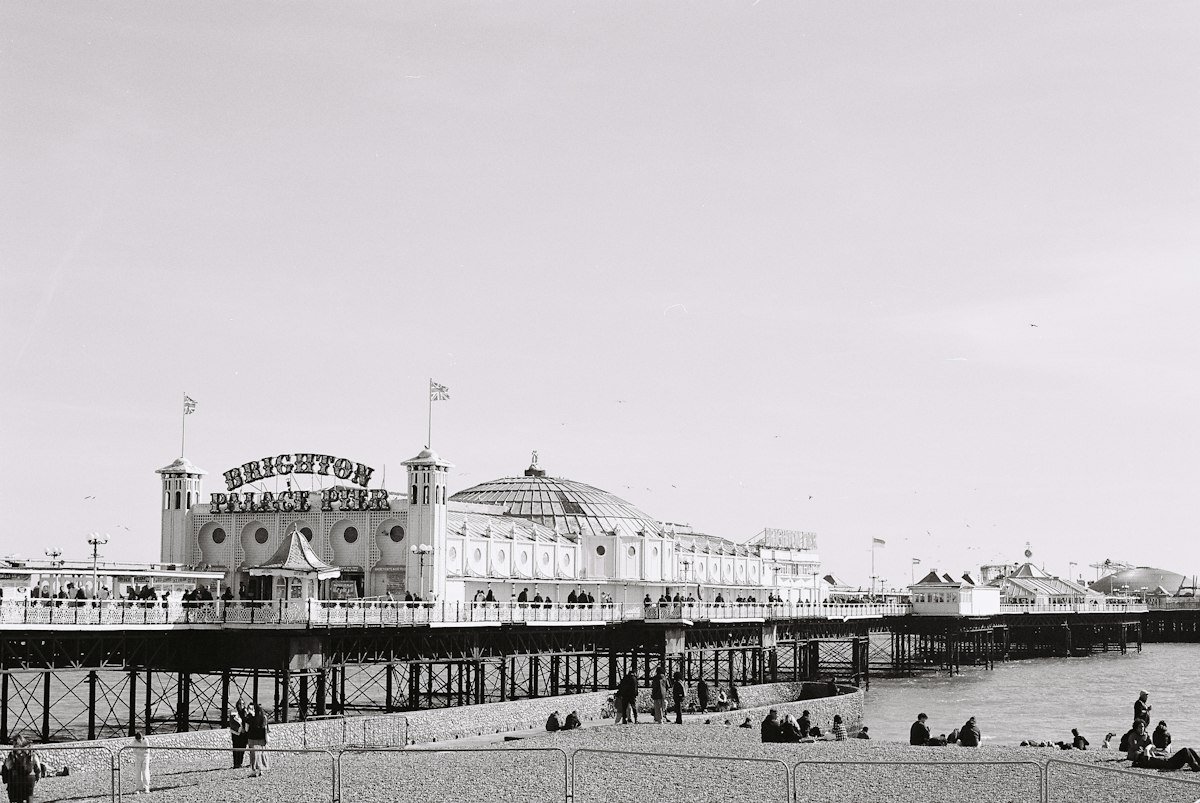 Brighton Palace Pier with visitors on the pebble beach below, an accessible UK seaside destination